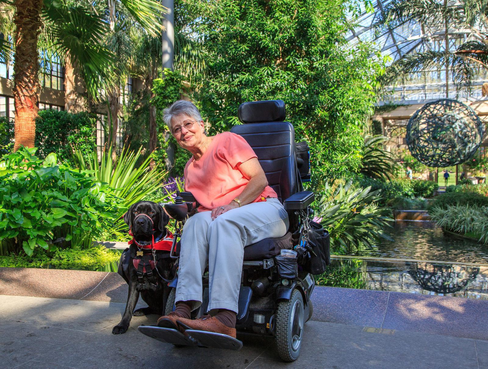 Woman posing with her service dog in her power wheelchair